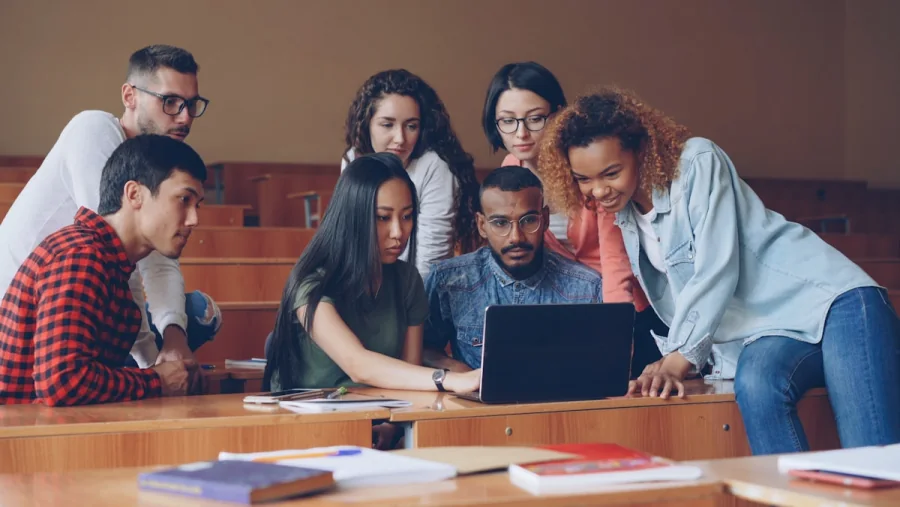 Students collaborating around a laptop in a modern classroom
